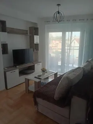 a living room with a bed and a tv and a table at Apartmani Vrnjacka Banja in Vrnjci