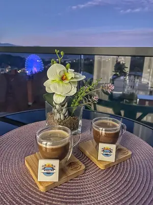 a table with two cups of coffee and a vase with flowers at Apartman NIKOLINA in Vrnjačka Banja