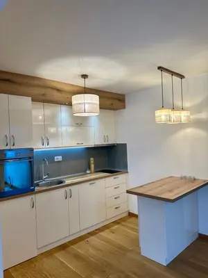 a kitchen with white cabinets and a sink and two lights at VIP House 4 in Vrnjačka Banja