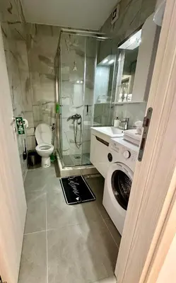 a bathroom with a toilet sink and a washing machine at Vidolux Studio - Free Garage and Fast WiFi in Niš