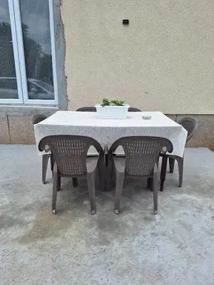 a table with two chairs and a bowl of flowers on it at Tomić