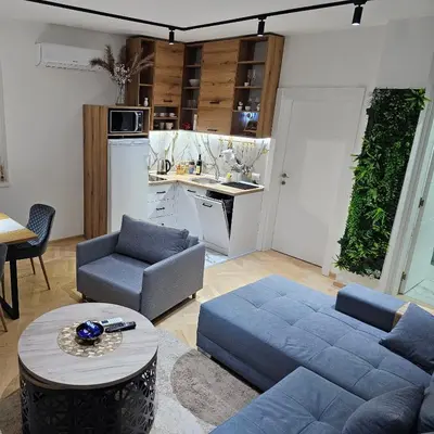 a living room with a blue couch and a kitchen at Apartmani Giga in Vrnjci