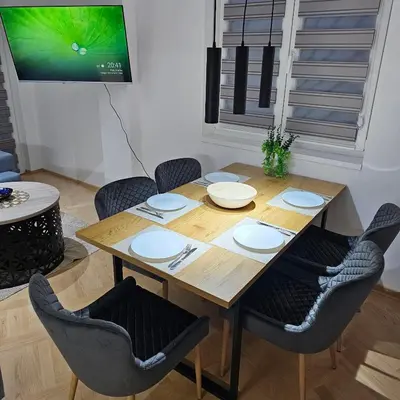 a dining room table with chairs and a tv at Apartmani Giga in Vrnjci