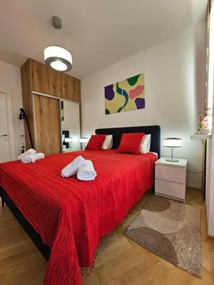 a bedroom with a red bed with two towels on it at Apartmani Giga in Vrnjci