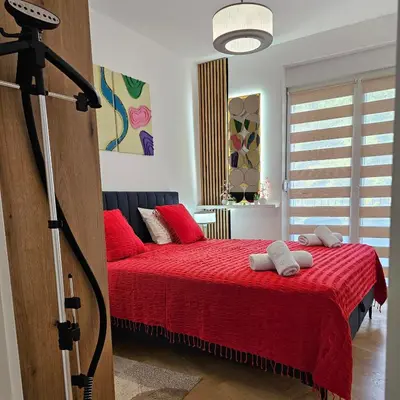 a bedroom with a red bed with red pillows at Apartmani Giga in Vrnjci