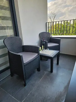 two chairs and a table with a bottle of wine on a balcony at Apartmani Giga in Vrnjci