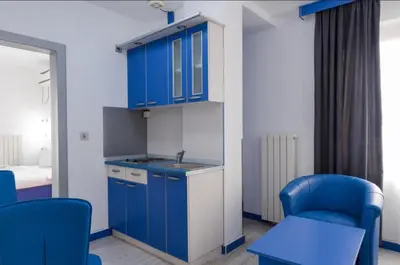 a kitchen with blue cabinets and a sink and chairs at Apartmani Šumadija 17 in Vrnjačka Banja
