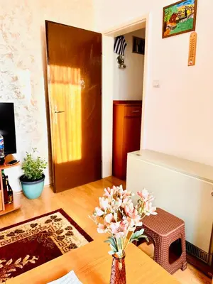 a room with a door and a table with flowers at Apartman Aki in Vlasotince