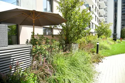 a garden with an umbrella next to a building at Residence LUX in Niš