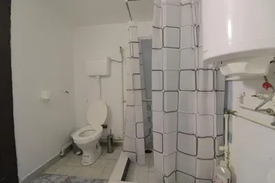 a white bathroom with a toilet and a sink at Etno Deša Apartmani in Dimitrovgrad
