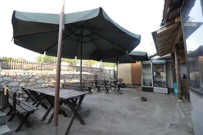a picnic table with an umbrella in front of a store at Etno Deša Apartmani in Dimitrovgrad