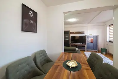 a living room with a wooden table and green chairs at Apartman ANJA LUX01 in Pirot