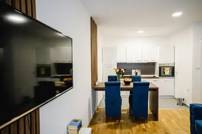a kitchen with a table and blue chairs at Lilys LUX apartman in Vrnjačka Banja