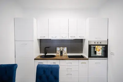 a white kitchen with white cabinets and a sink at Lilys LUX apartman in Vrnjačka Banja