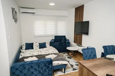 a bedroom with a bed and two blue chairs at Lilys LUX apartman in Vrnjačka Banja