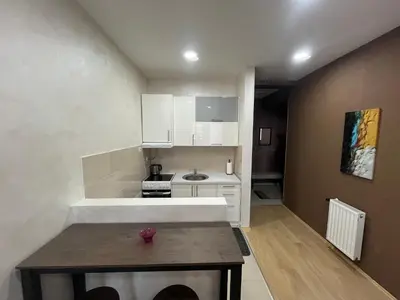 a small kitchen with white cabinets and a table at Sofija apartmani in Paraćin