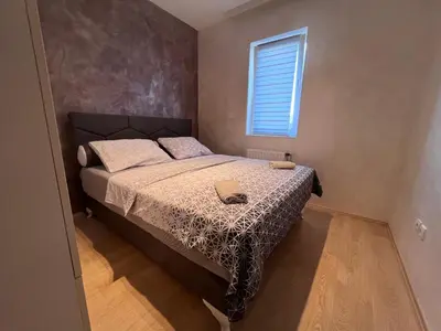 a small bedroom with a bed with a window at Sofija apartmani in Paraćin