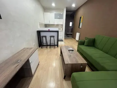 a living room with a green couch and a table at Sofija apartmani in Paraćin
