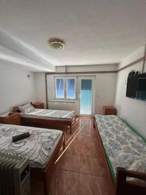 a room with two beds and a tv on the wall at Studio - Apartmani 3 in Jošanička Banja