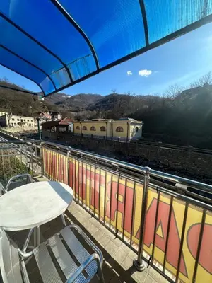 a table and chairs on a balcony with a train at Studio - Apartmani 3 in Jošanička Banja