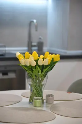 a vase of yellow and white flowers on a table at Urban Elegance SPA Studio in Niš