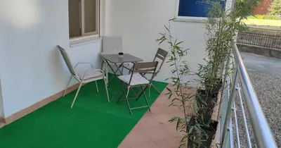 a patio with a table and chairs on a green floor at WellNest Niš Self Check-in & Parking I Moderan, miran apartman plus radni kutak in Niš