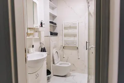 a white bathroom with a toilet and a sink at WellNest Niš Self Check-in & Parking I Moderan, miran apartman plus radni kutak in Niš