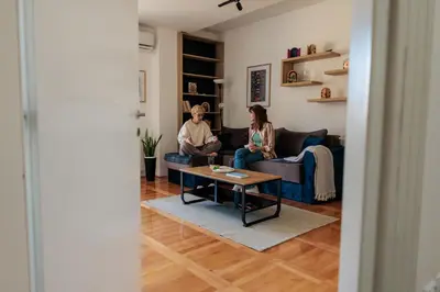 two people sitting on couches in a living room at WellNest Niš Self Check-in & Parking I Moderan, miran apartman plus radni kutak in Niš