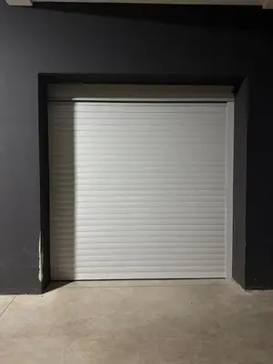 a white garage door in a black wall at Nest24- cozy apartment with terrace and private garage in Niš