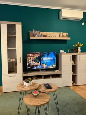 a living room with two tables and a flat screen tv at Nest24- cozy apartment with terrace and private garage in Niš