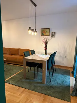 a dining room table with chairs and a couch at Nest24- cozy apartment with terrace and private garage in Niš