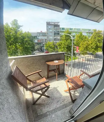 a balcony with two wooden benches and a table at City Fontana in Kruševac