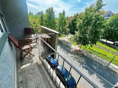 a balcony with a bench and a car on a street at City Fontana in Kruševac