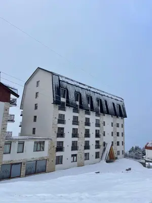 a large white building with snow on the roof at Evergreen Lux in Kopaonik