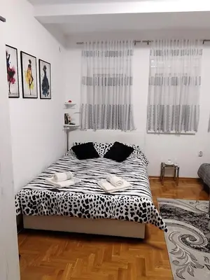 a bedroom with a bed with black and white sheets at Studio apartman BB4 in Vrnjačka Banja
