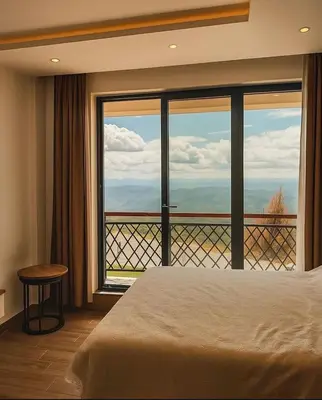 a bedroom with a bed and a large window at Hafsah Hill Kopaonik in Kopaonik