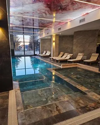 a large swimming pool with chairs and a large window at Hafsah Hill Kopaonik in Kopaonik