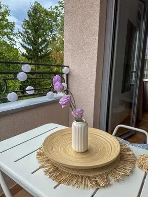 a table with a white vase with purple flowers on it at Apartman 7 in Vrnjačka Banja