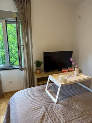 a bedroom with a bed with a table and a tv at Apartman 7 in Vrnjačka Banja
