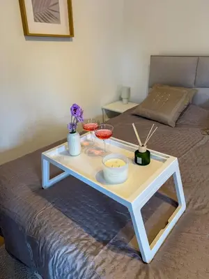a white coffee table with two glasses on a bed at Apartman 7 in Vrnjačka Banja