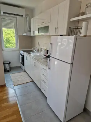 a white kitchen with a refrigerator and a sink at Apartman IRIS in Pirot