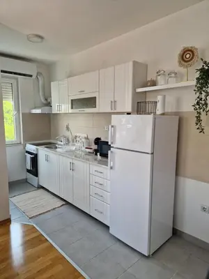 a kitchen with white cabinets and a white refrigerator at Apartman IRIS in Pirot