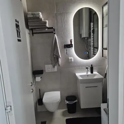 a bathroom with a toilet and a sink and a mirror at V i N Boutique Apartment in Niš