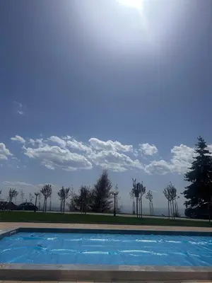 a blue swimming pool with trees in the background at UN lux - Residence Hill in Kopaonik