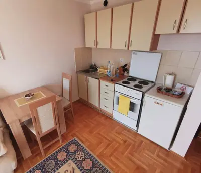 a small kitchen with a white stove and a table at Apartman PK Vrnjačka Banja in Vrnjačka Banja
