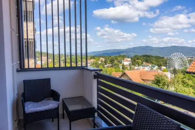 a balcony with two chairs and a table and a view at Apartman Vrnjacka Banja in Vrnjačka Banja