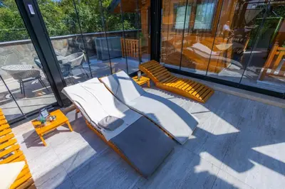 a patio with two chairs and a table and windows at Apartman Vrnjacka Banja in Vrnjačka Banja