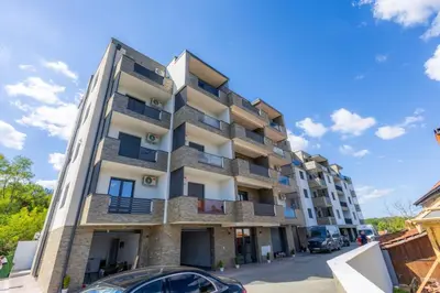 an apartment building with cars parked in front of it at Apartman Vrnjacka Banja in Vrnjačka Banja