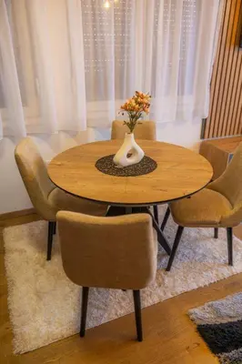 a wooden table with chairs and a vase with flowers on it at Apartman Vrnjacka Banja in Vrnjačka Banja