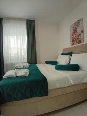 a bedroom with two beds with green and white sheets at Wing Apartman Jagodina in Jagodina